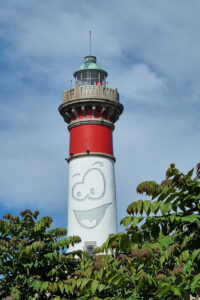 Montage photo du phare de Ouistreham qui arbore un visage cartoonesque joyeux