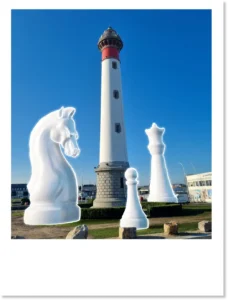 Montage photo du phare de Ouistreham entouré de pièces d'échecs géantes