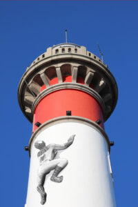 Montage photo du phare de Ouistreham qui se fait escalader par l'homme araignée