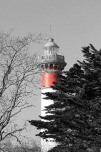 Photo noir et blanc du phare de Ouistreham dont la seule couleur présente est le rouge.